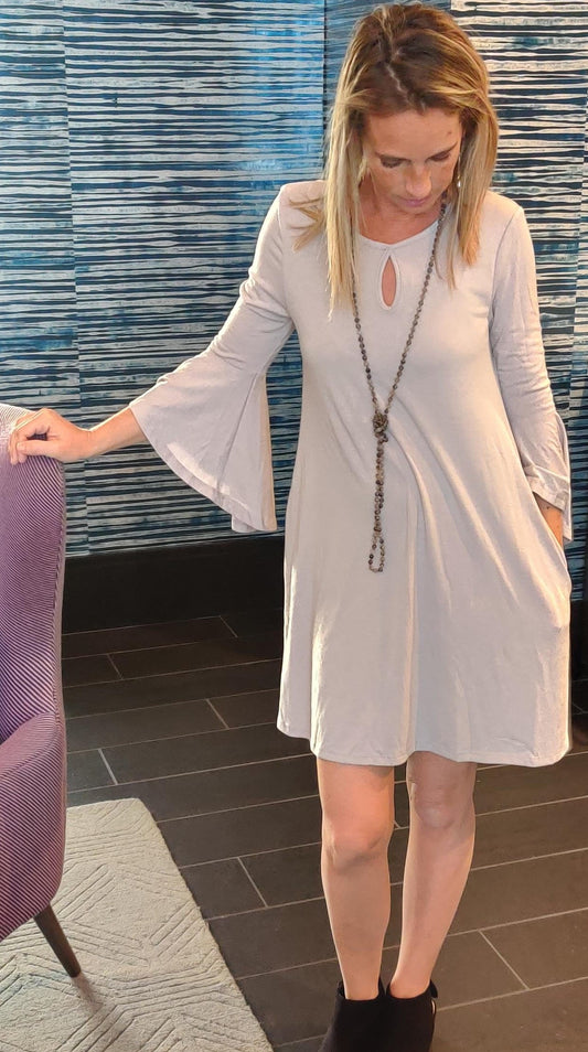 Vestido gris claro con volantes en las mangas, abertura y bolsillos